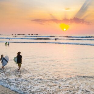 Zwei Surfer, die während eines Sonnenuntergangs in Costa Rica ins Wasser zurückgehen.