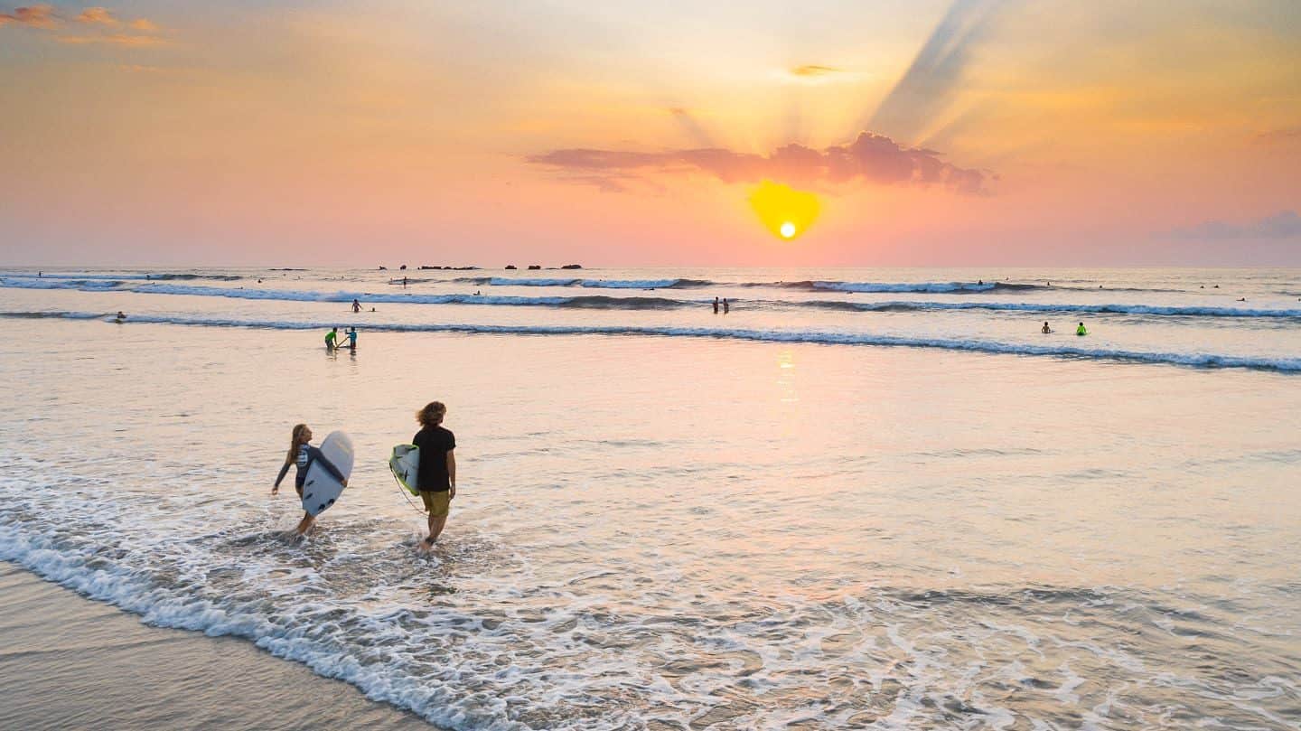 Deux surfeurs qui rentrent à l'eau pendant un couché de soleil au Costa-Rica