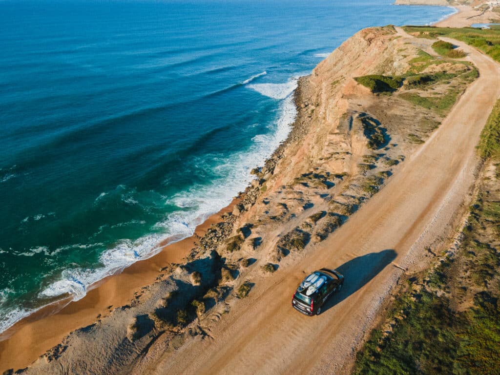 Surf spot on the edge of a cliff in Portugal with a car driving over the cliff