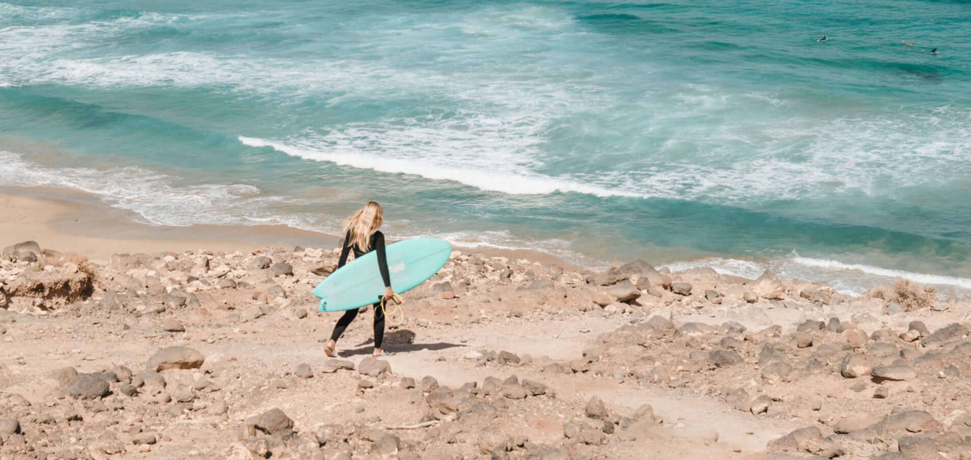 Surfeuse blonde allant sur le spot de surf à pied à Gran Canaria dans les Îles Canaries